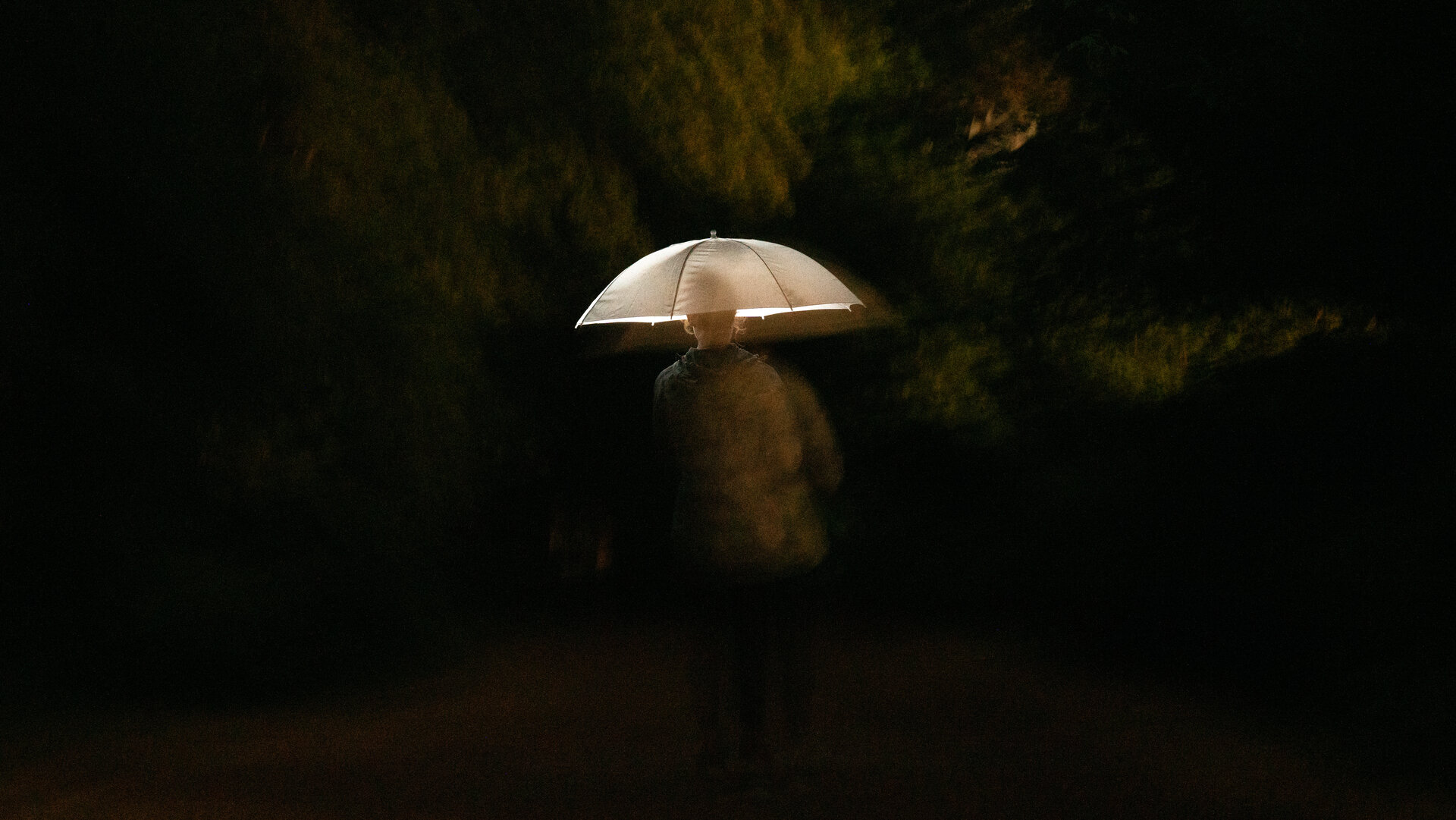 Person mit Regenschirm bei Nacht